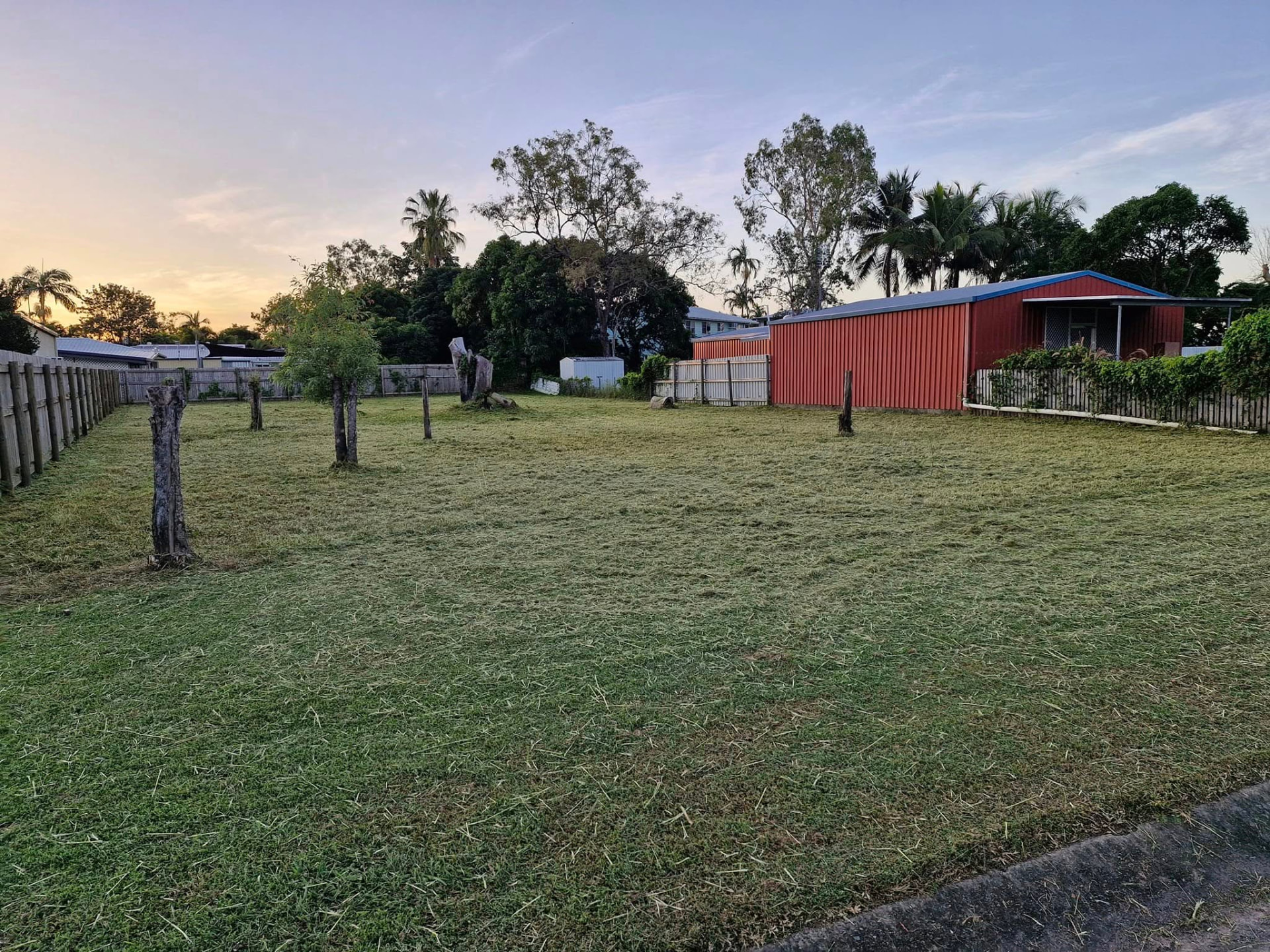 After: the same Townsville block fully mown, cut short and level at sunset